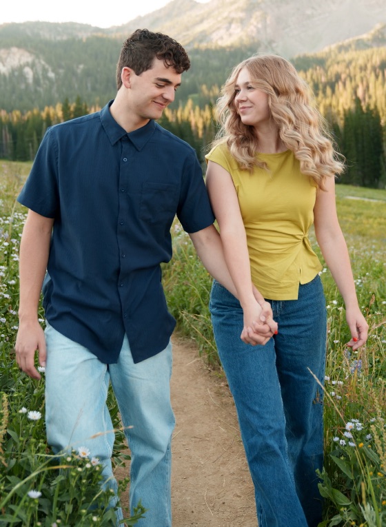 Emmaline and Clark Jr. walking hand in hand through a wildflower meadow